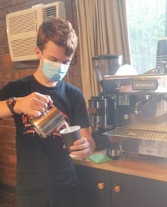 Student pouring milk into coffee cup