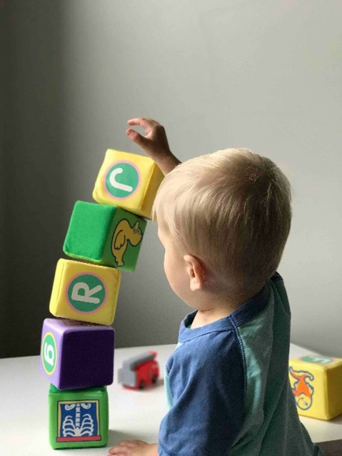 A baby stacking toy blocks and the blocks fall